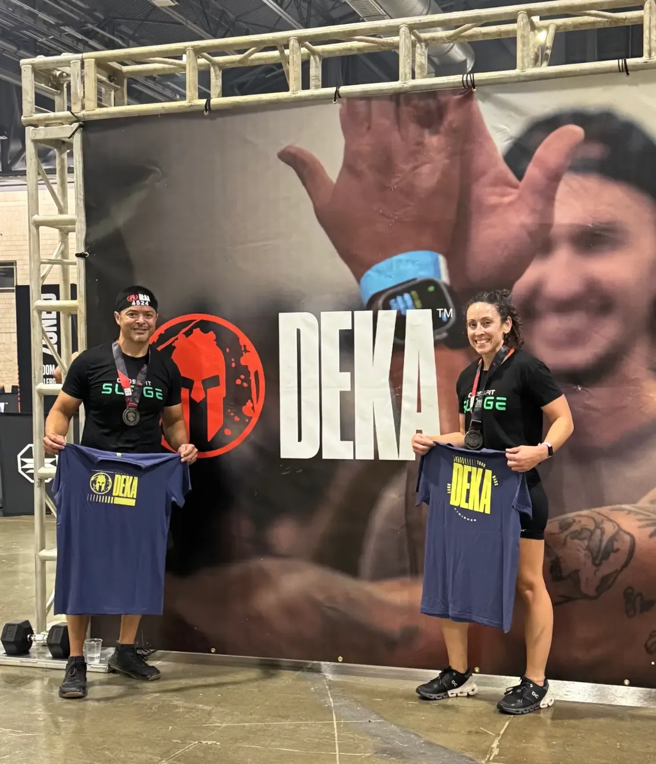 Two CrossFit Surge athletes holding DEKA shirts at a DEKA event
