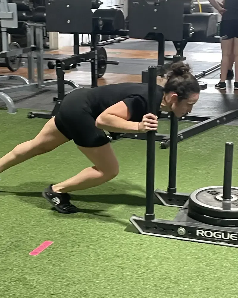 An athlete pushing a sled on turf