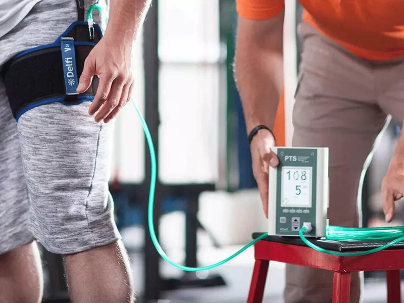 Physical therapist applying a blood flow restriction cuff during strength training