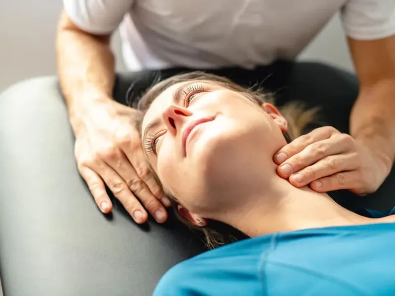 Physical therapist assessing a patient's neck movement and posture